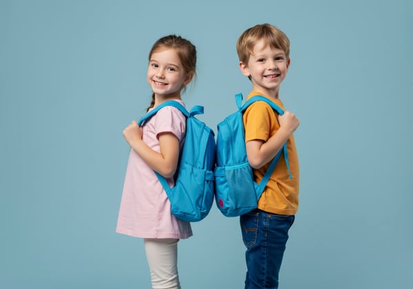 two smiling children with blue backpacks